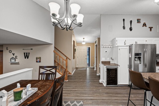 dining area with a textured ceiling, wood finished floors, stairway, wine cooler, and a chandelier