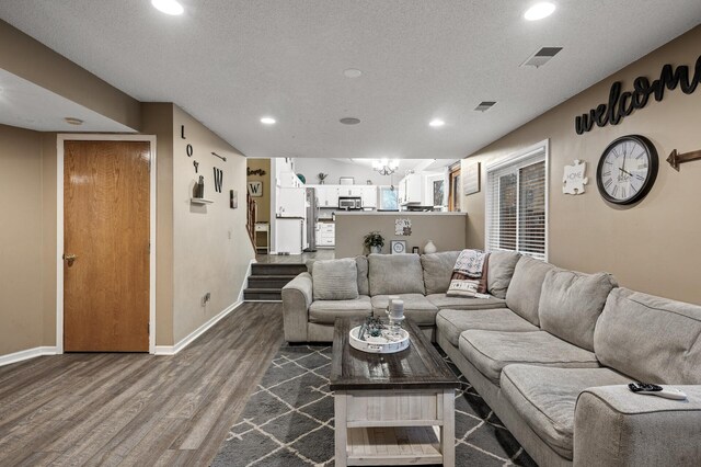 living area with visible vents, baseboards, dark wood-type flooring, and a textured ceiling