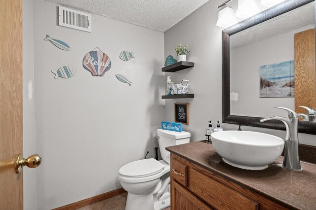 half bath with vanity, baseboards, visible vents, a textured ceiling, and toilet