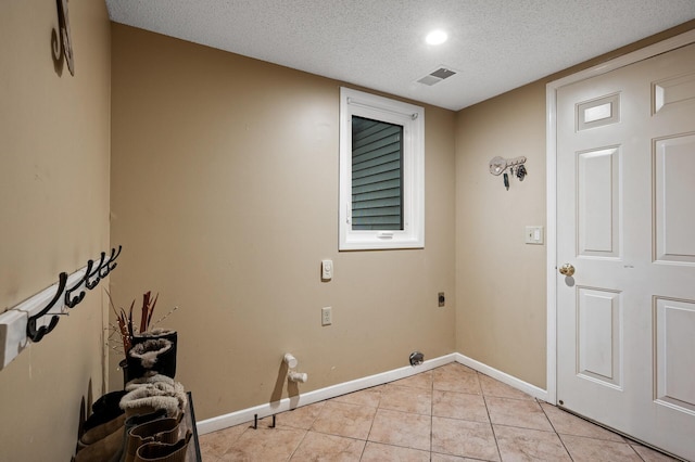 washroom with light tile patterned floors, visible vents, hookup for an electric dryer, laundry area, and a textured ceiling