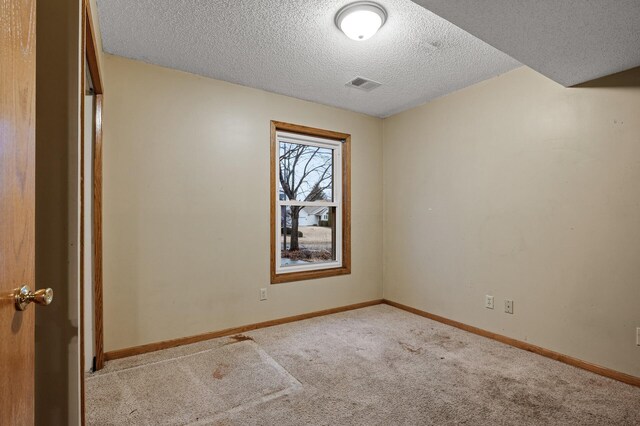 spare room with visible vents, baseboards, a textured ceiling, and carpet flooring