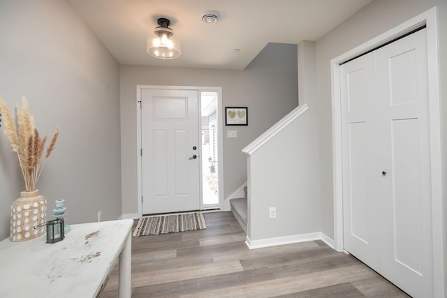 entryway featuring stairway, baseboards, and light wood-style floors