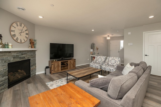 living room featuring recessed lighting, baseboards, a stone fireplace, and wood finished floors