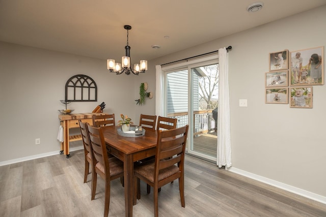 dining space featuring a notable chandelier, baseboards, and light wood-type flooring