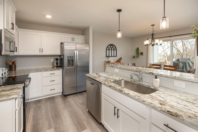 kitchen featuring a sink, backsplash, white cabinetry, stainless steel appliances, and light wood-style floors