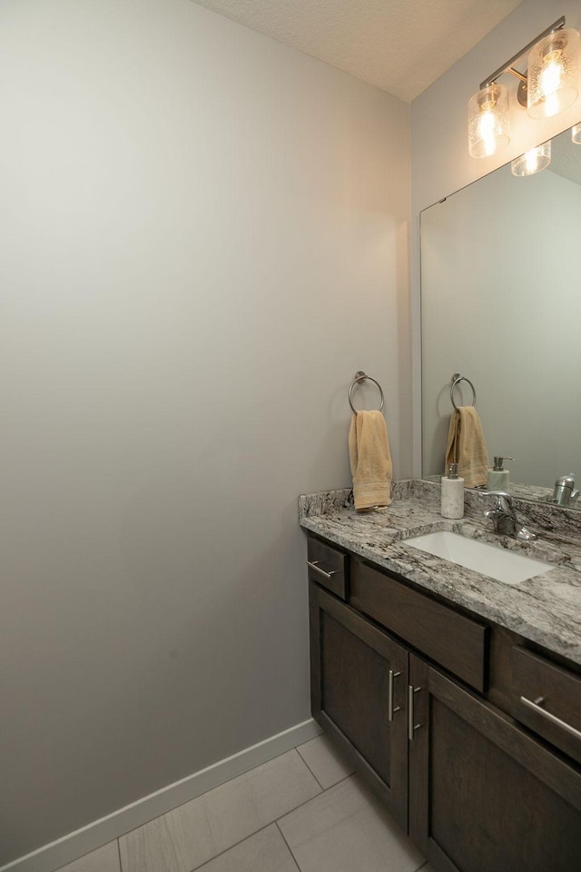 bathroom with baseboards, vanity, and tile patterned flooring