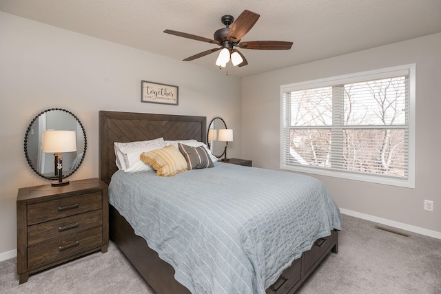 bedroom featuring visible vents, light colored carpet, baseboards, and ceiling fan