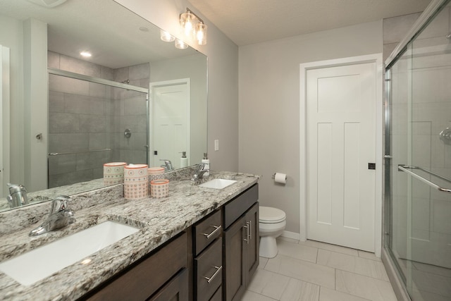 bathroom featuring a shower stall, toilet, double vanity, and a sink