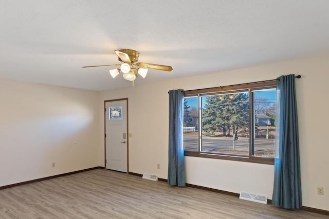 unfurnished room with wood finished floors, visible vents, and baseboards