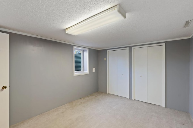 basement with visible vents, ornamental molding, a textured ceiling, and carpet floors