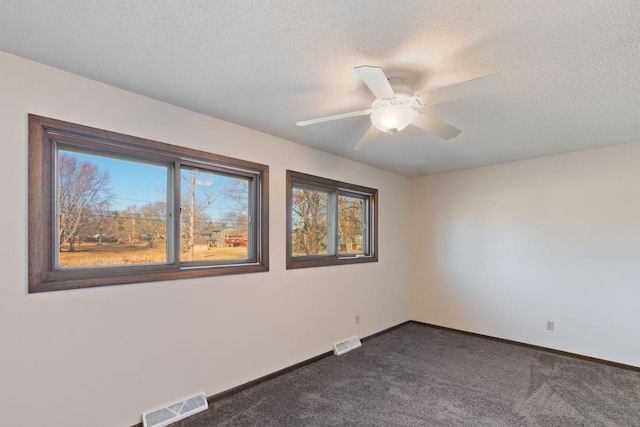 empty room with visible vents, dark carpet, and baseboards