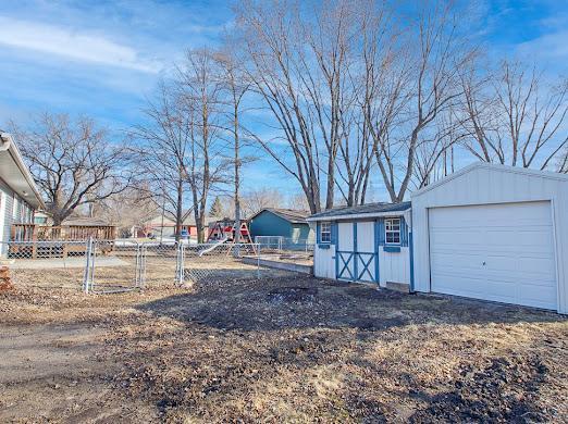 view of yard featuring a garage, an outdoor structure, and fence