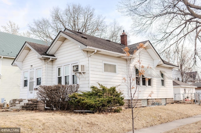 view of side of home with a shingled roof, entry steps, and a chimney