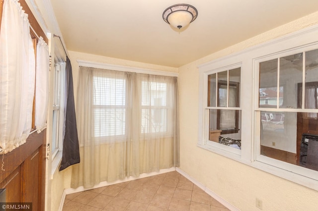 unfurnished room with light tile patterned flooring and baseboards