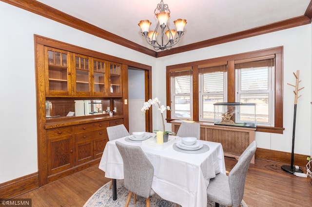 dining room featuring an inviting chandelier, crown molding, wood finished floors, and baseboards