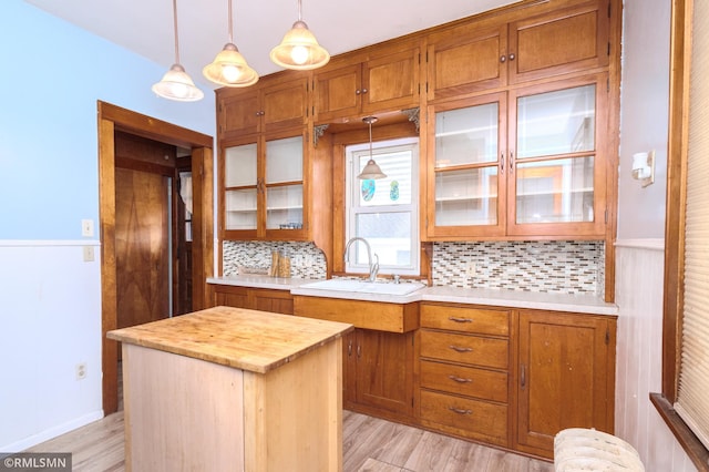 kitchen with decorative light fixtures, brown cabinets, light wood-style floors, and a sink