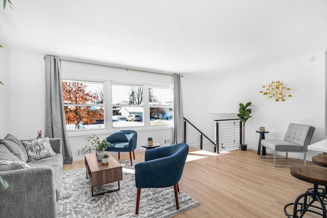 sitting room featuring baseboards, an upstairs landing, light wood-style floors, and visible vents