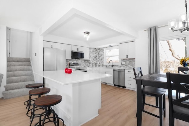 kitchen featuring decorative backsplash, a breakfast bar area, stainless steel appliances, and light wood-style floors