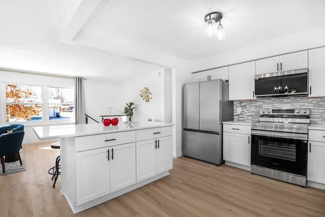 kitchen featuring stainless steel appliances, light countertops, white cabinets, light wood-style floors, and tasteful backsplash