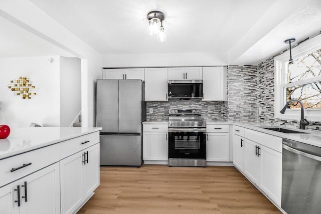 kitchen featuring a sink, stainless steel appliances, light countertops, light wood-style floors, and white cabinetry