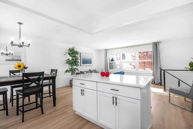 kitchen with light wood-style floors, a chandelier, a center island, and white cabinetry