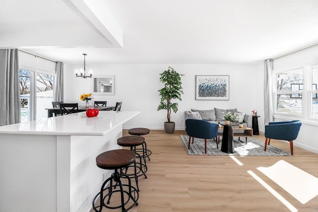 kitchen featuring baseboards, light wood-style floors, a breakfast bar area, and light countertops