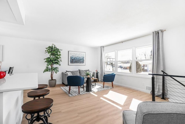 living room featuring visible vents, baseboards, and light wood-style floors