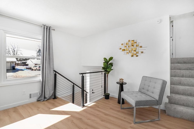 sitting room featuring visible vents, baseboards, wood finished floors, and stairs