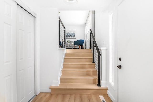 stairs with wood finished floors, visible vents, and baseboards