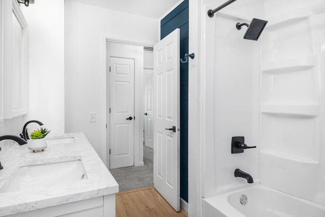 full bathroom featuring double vanity, shower / washtub combination, wood finished floors, and a sink