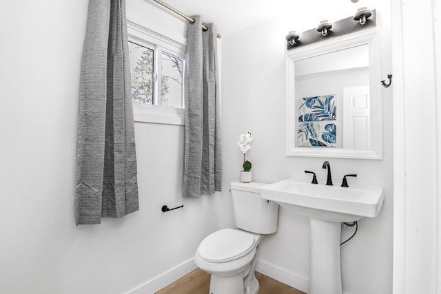 bathroom with a sink, toilet, baseboards, and wood finished floors