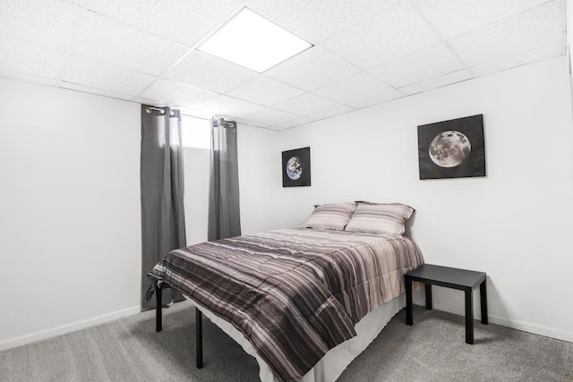 bedroom with a drop ceiling, baseboards, and carpet floors