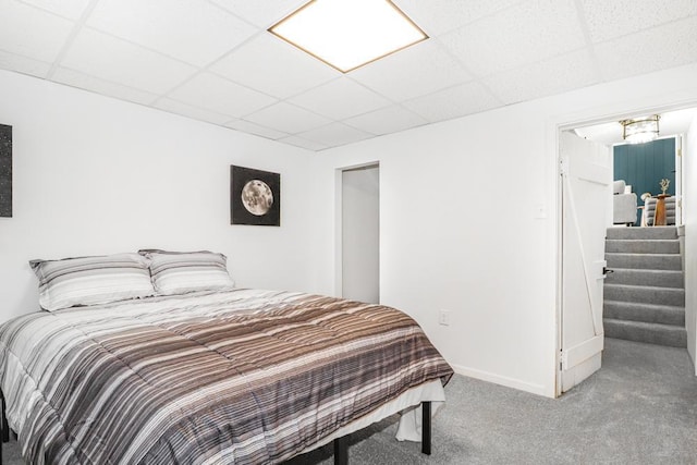 carpeted bedroom with a paneled ceiling and baseboards