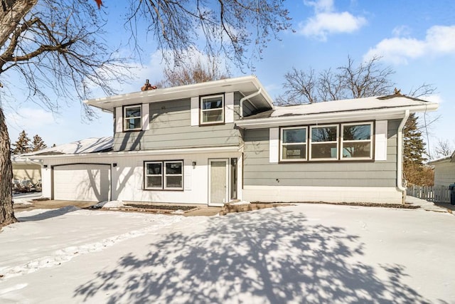 tri-level home featuring fence, a garage, driveway, and a chimney