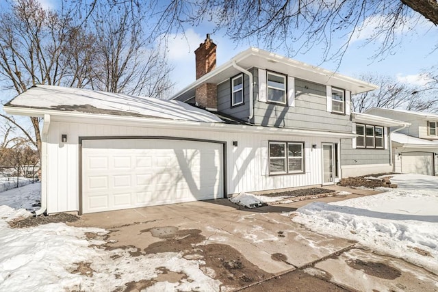 view of snow covered exterior featuring board and batten siding, a garage, driveway, and a chimney