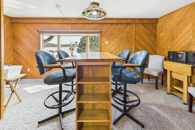 dining space with wooden walls, a textured ceiling, and carpet