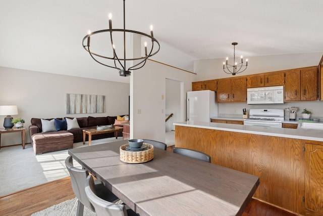 dining room with a chandelier, light wood-style flooring, and lofted ceiling