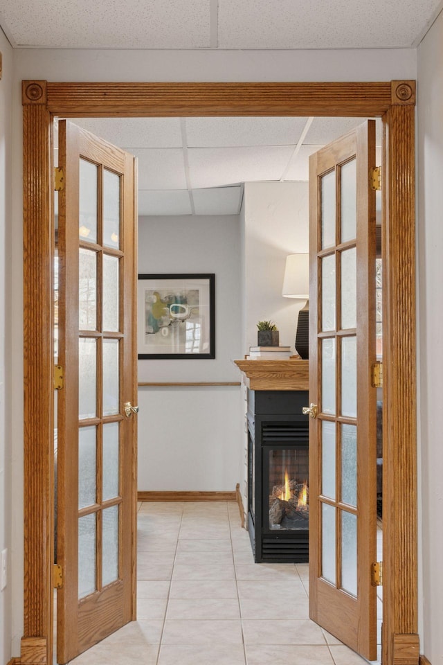 hallway featuring tile patterned flooring, french doors, a paneled ceiling, and baseboards