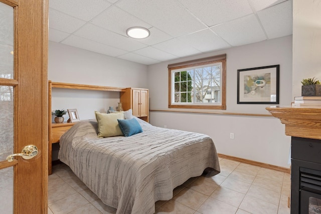 bedroom featuring light tile patterned floors, a paneled ceiling, and baseboards