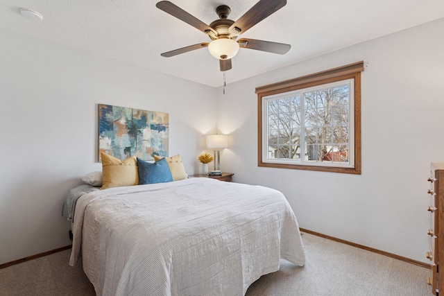 carpeted bedroom featuring a ceiling fan, baseboards, and a textured ceiling