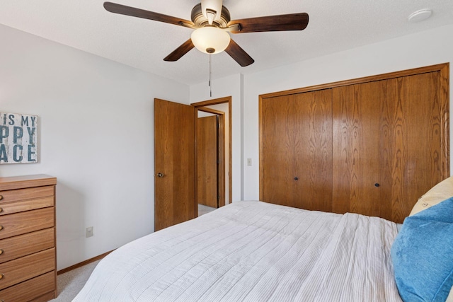 bedroom featuring baseboards, light carpet, a closet, a textured ceiling, and a ceiling fan