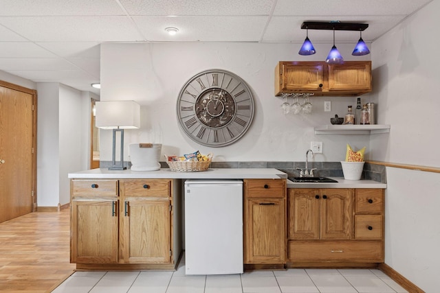 kitchen featuring fridge, a paneled ceiling, light countertops, and a sink