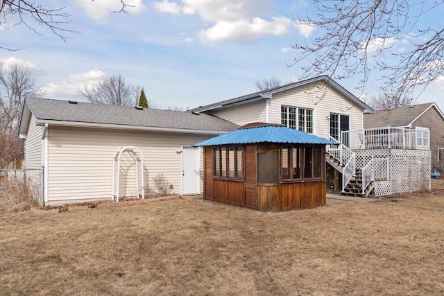 rear view of property featuring a wooden deck, a yard, a shingled roof, and stairway