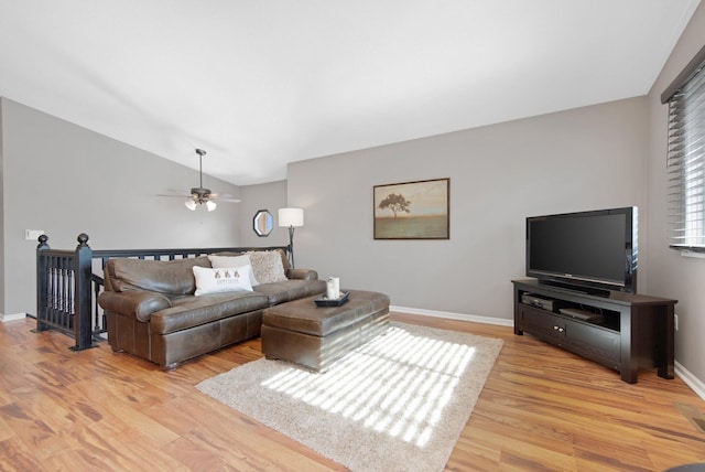 living area with baseboards, light wood-style floors, a ceiling fan, and vaulted ceiling