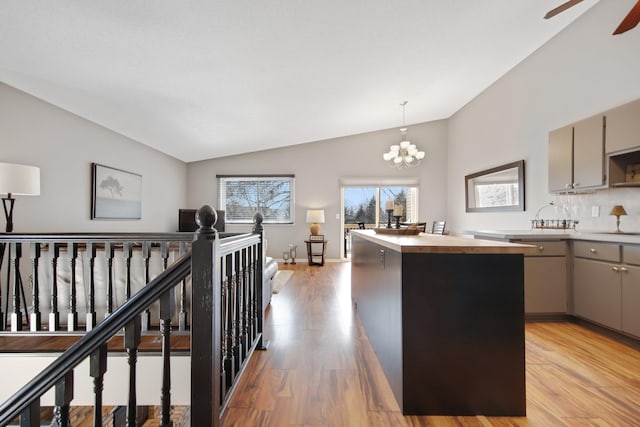 interior space with an inviting chandelier, lofted ceiling, light wood-style flooring, and an upstairs landing