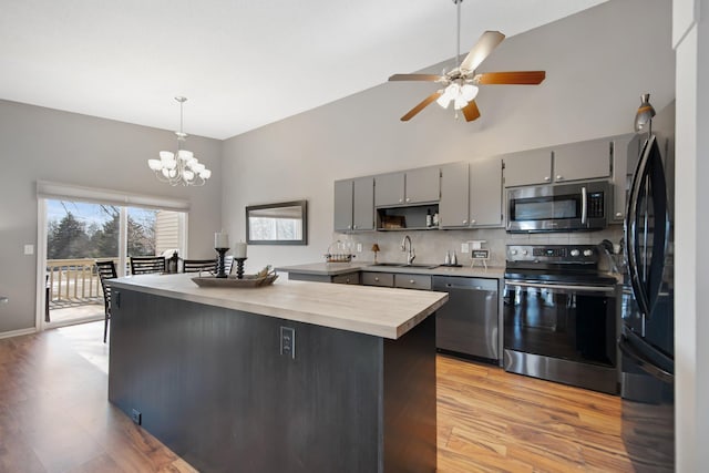 kitchen featuring a sink, high vaulted ceiling, appliances with stainless steel finishes, and gray cabinets