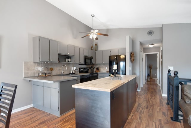 kitchen featuring tasteful backsplash, gray cabinetry, black appliances, a ceiling fan, and a sink