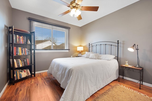 bedroom featuring a ceiling fan, baseboards, and wood finished floors