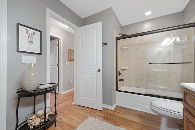 full bath featuring enclosed tub / shower combo, toilet, vanity, and wood finished floors