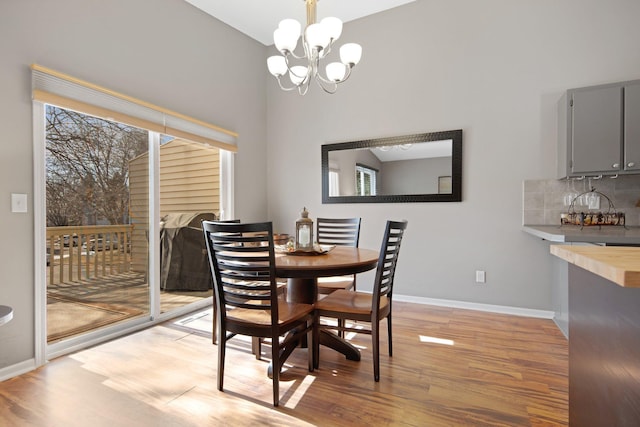 dining space featuring a wealth of natural light, light wood-type flooring, baseboards, and a notable chandelier